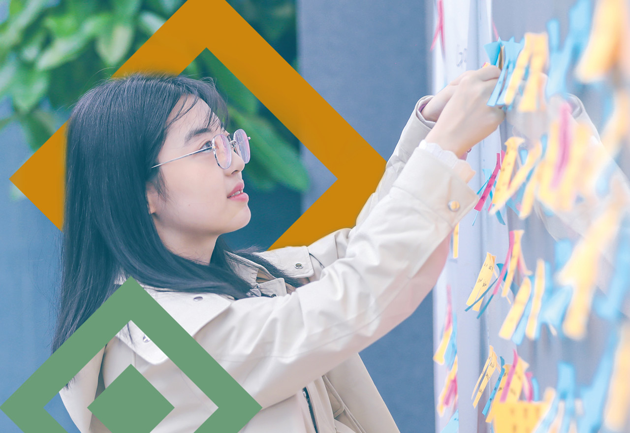 An experience designer pinning up a post-it on a wall full of colourful post-it notes